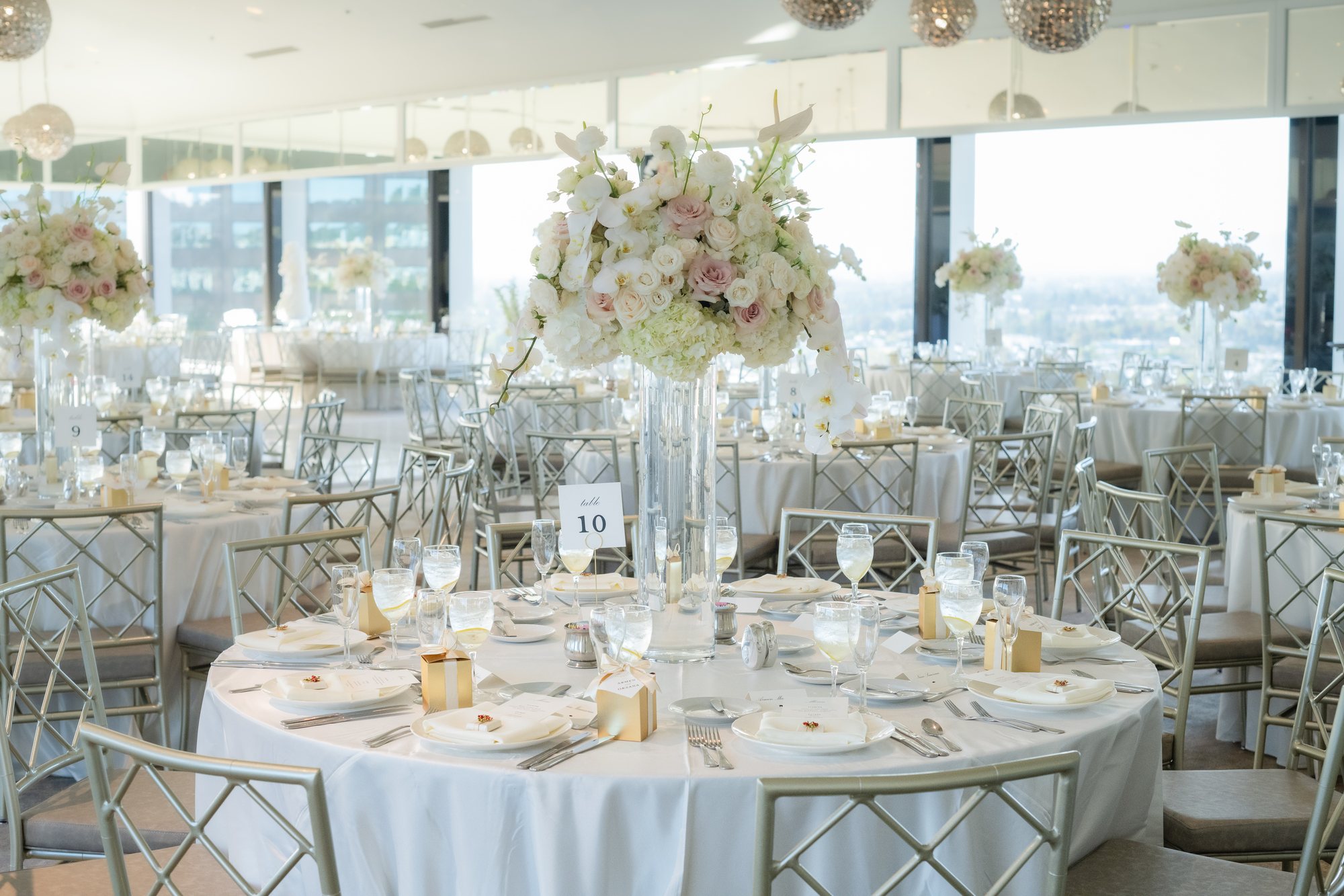 Ballroom wedding reception with floral centerpieces and an ocean view