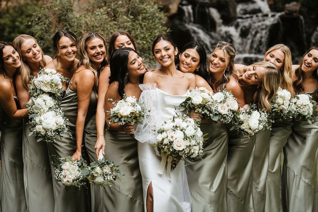 Bridesmaids in sage gowns holding white and green bouquets